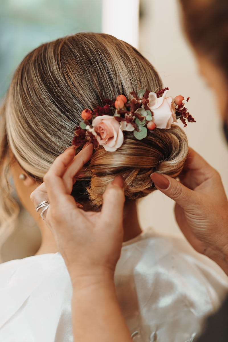 A close-up of a bride's elegant updo adorned with pink and red flowers, styled for a wedding.