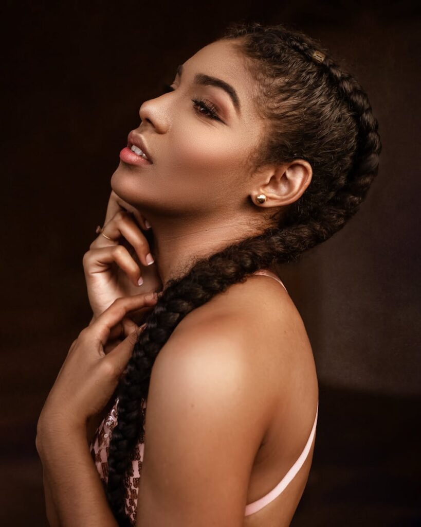 Side view of charming ethnic female with trendy makeup and hairstyle touching neck and looking away