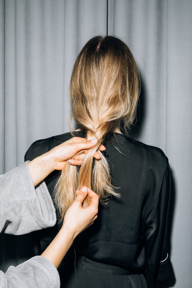 A person styling another's blonde hair during a cozy indoor pajama party.